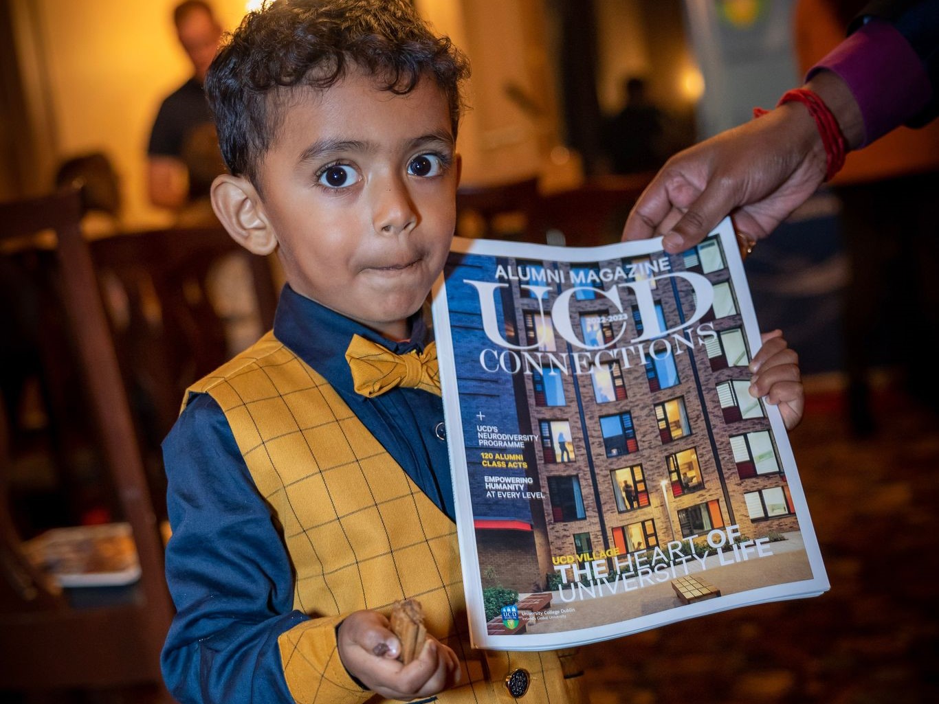 Young boy holds up a copy of the UCD alumni magazine at an alumni event in San Francisco