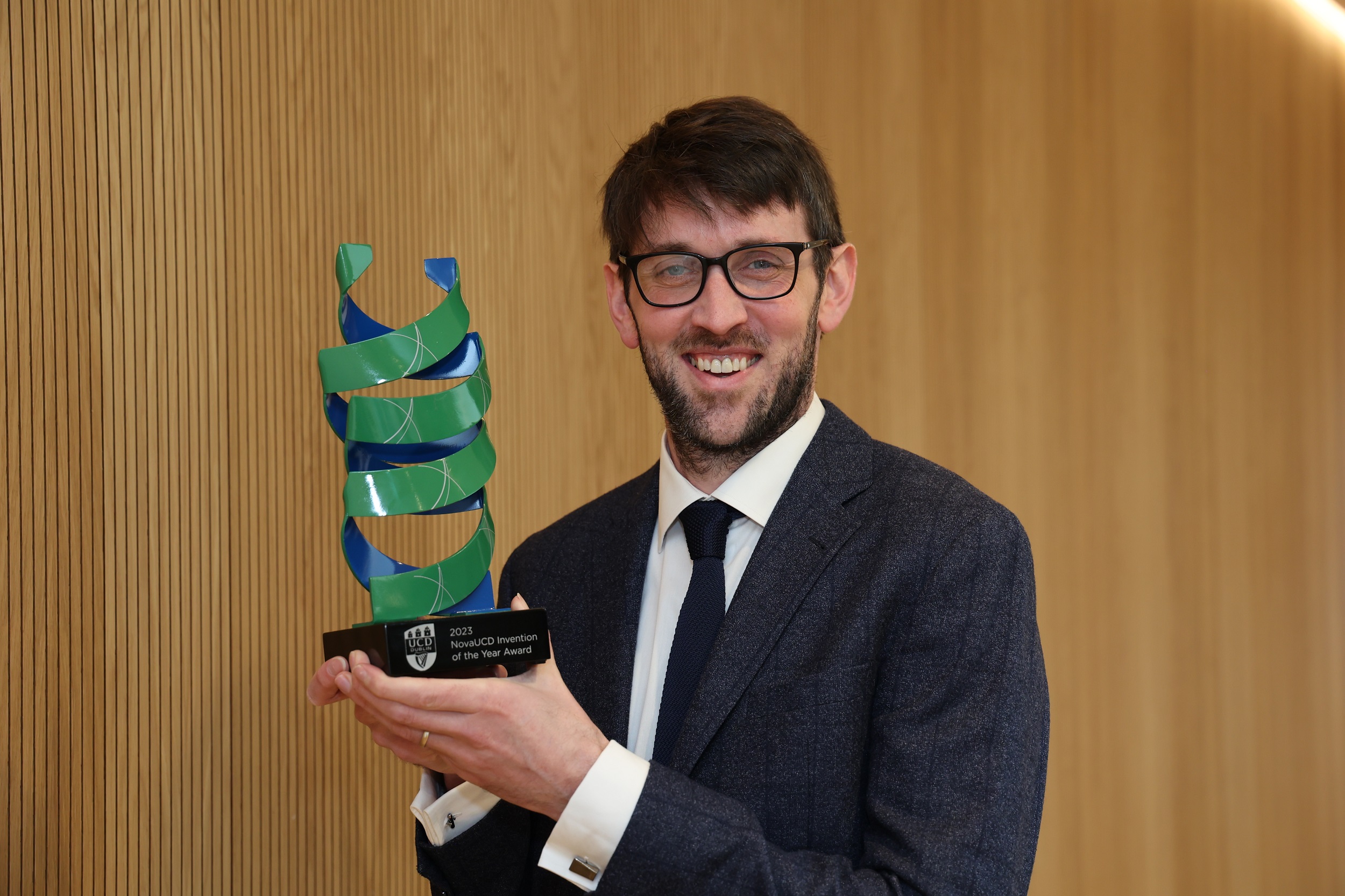 A man smiling and holding an award