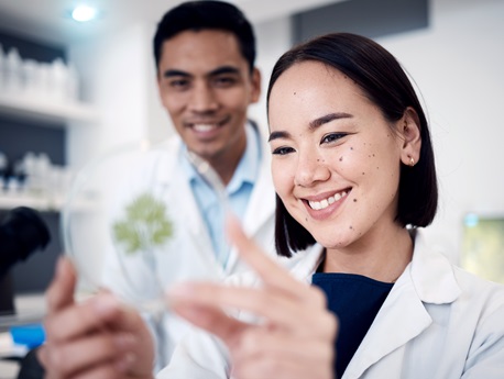 two people in lab coats looking at petri dish decorative image