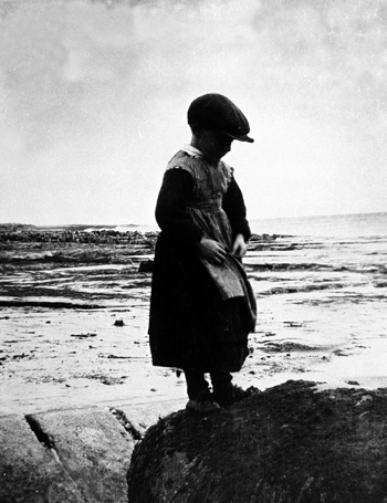 Boy in petticoat, Inis Meáin, County Galway, 1930. It is thought that young boys were sometimes dressed In skirts to protect them from fairy abduction. A belief existed that the fairies would choose boys before girls. (Photograph copyright National Folklore Collection, University College Dublin