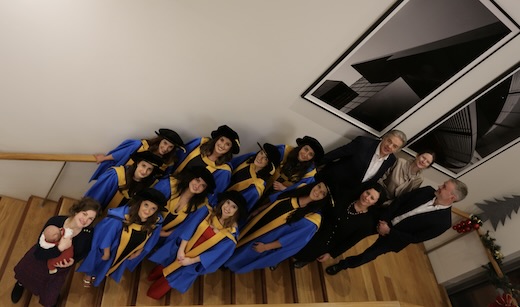 A group of graduates and staff on a stairs looking up at the camera