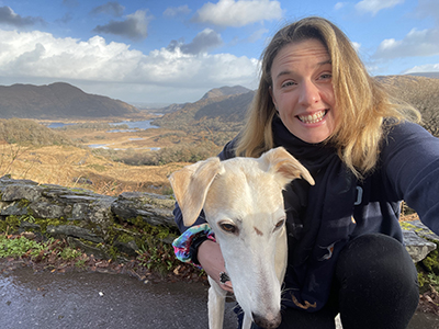 Eilidh Thomson and her dog in front of mountains and a lake