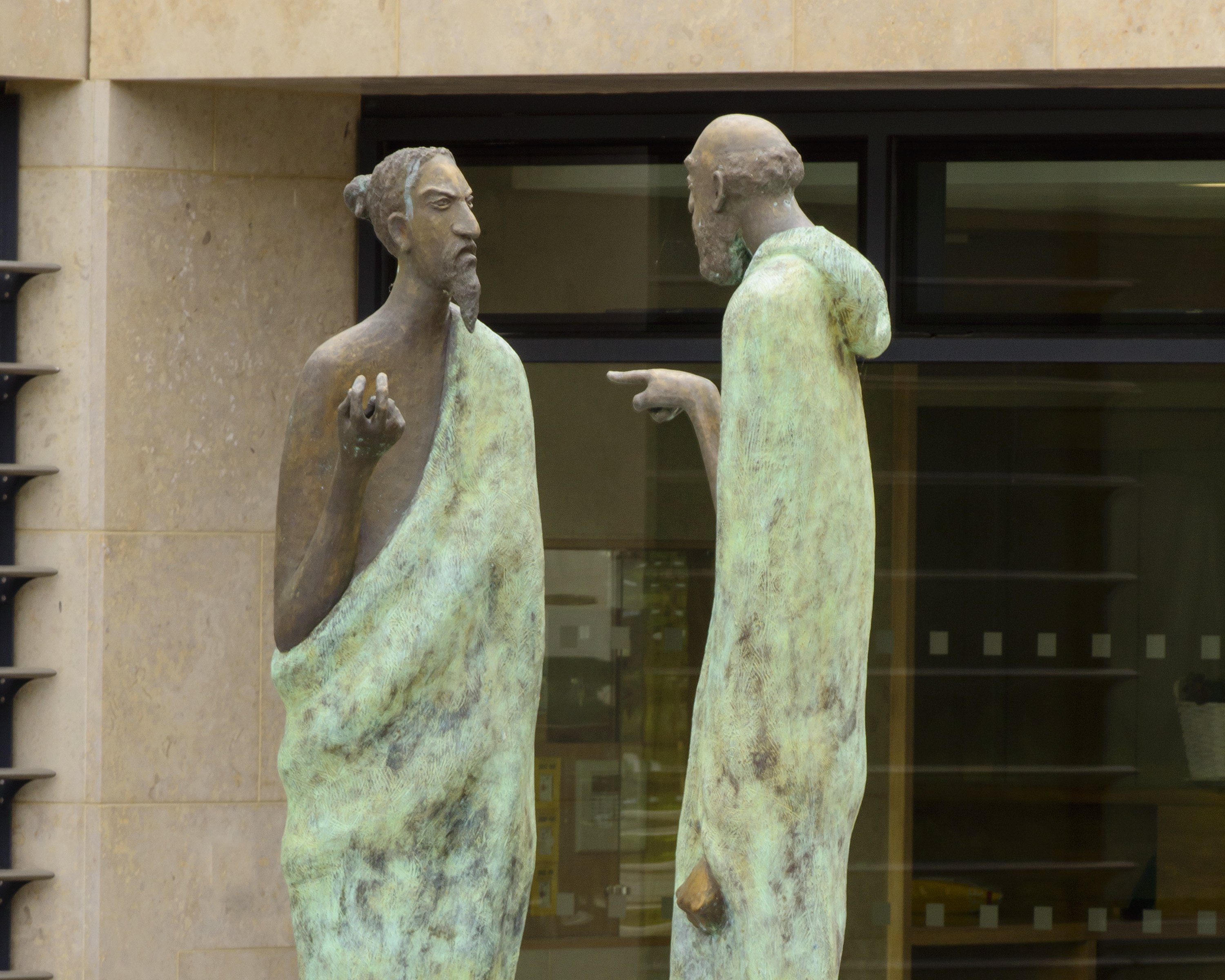 Two statues of people arguing and point at each other