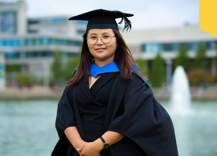Dipa Rai poses in front of the main lake at UCD on the day of her conferring ceremony
