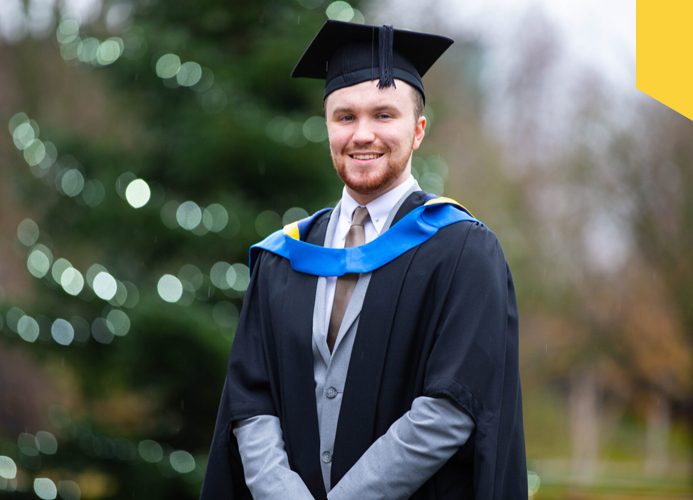 Luke Murphy stands in front of a Christmas tree on the day of his graduation from UCD