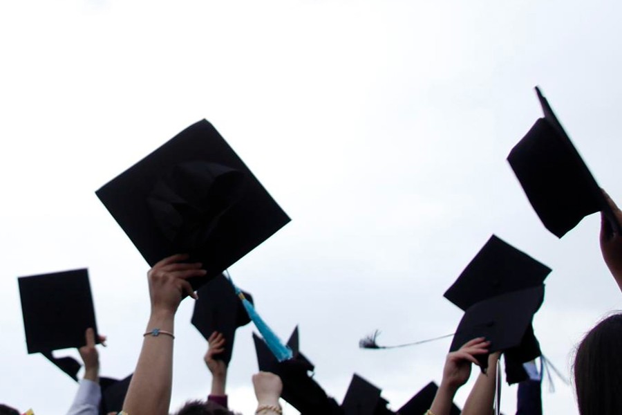 A photo of graduates holding their caps in the air.