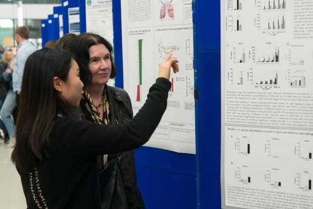 A student explains their poster to College Principal