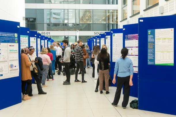 A group of students present their posters at symposium event