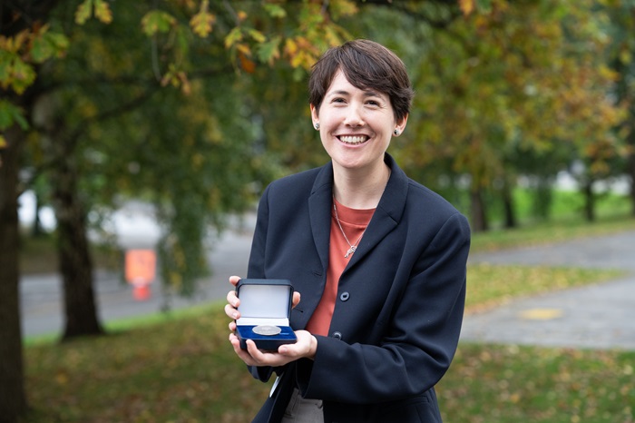 Woman smiling and holding a box with medal inside