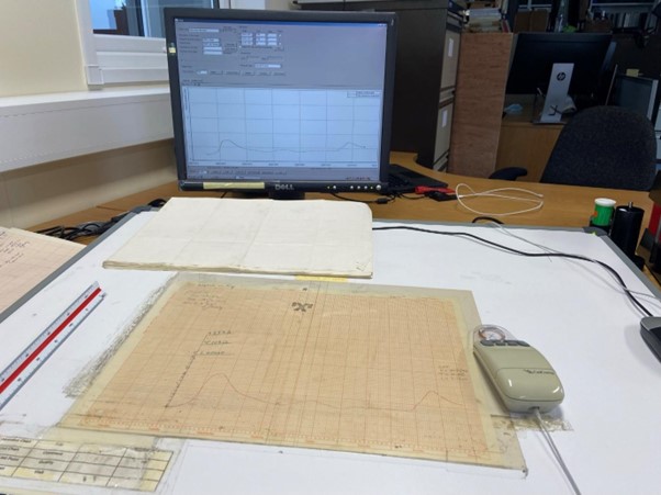 A computer screen, scanner, mouse and paper material showing the digitisation process