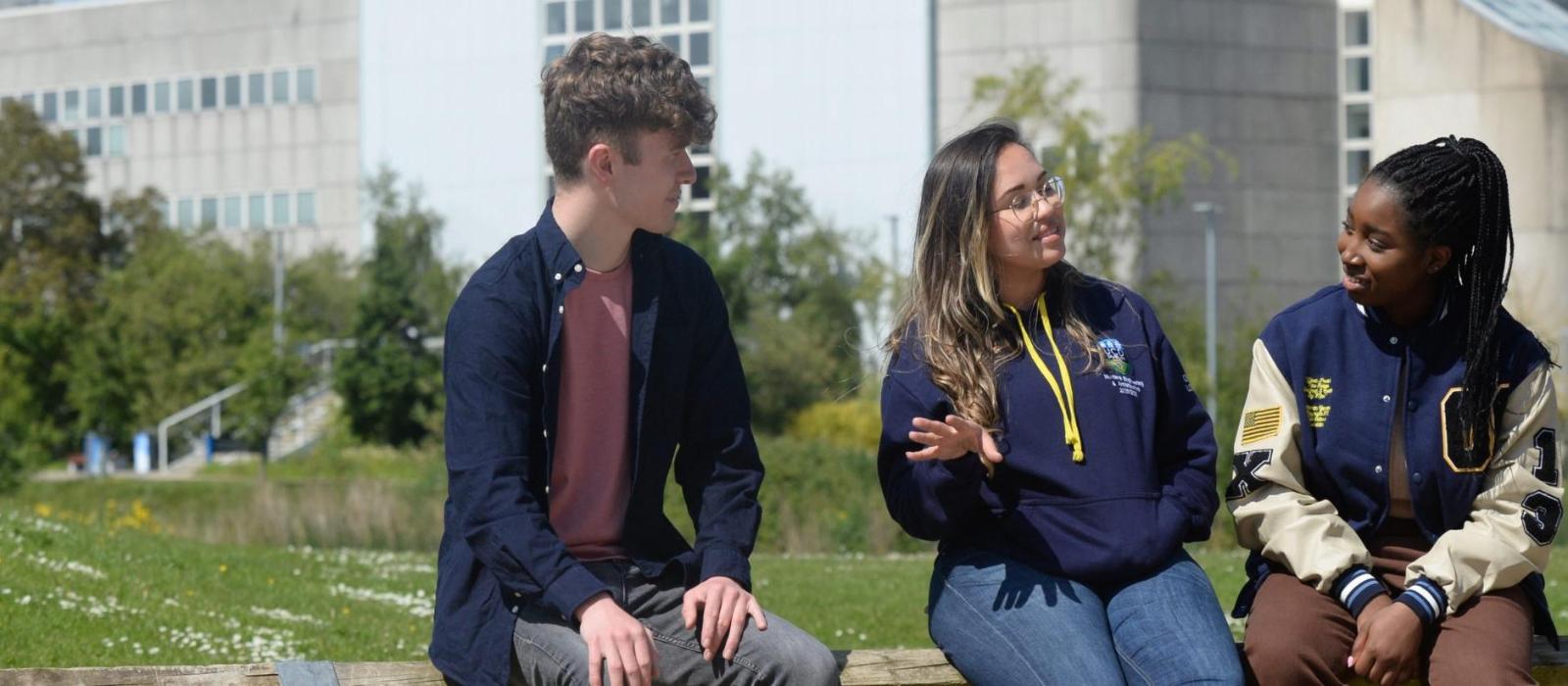 Three students sitting and talking outdoors