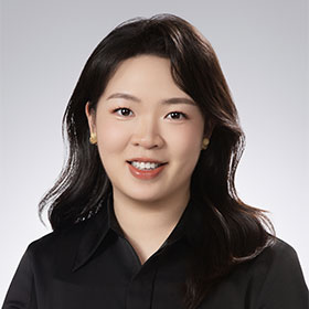 A young woman with mid-length brown hair and a black shirt smiles to camera.