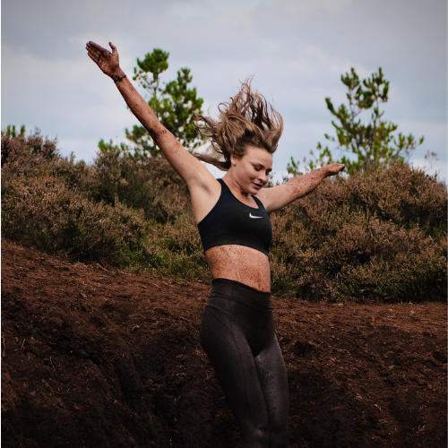 Girl jumps into a pile of mud.