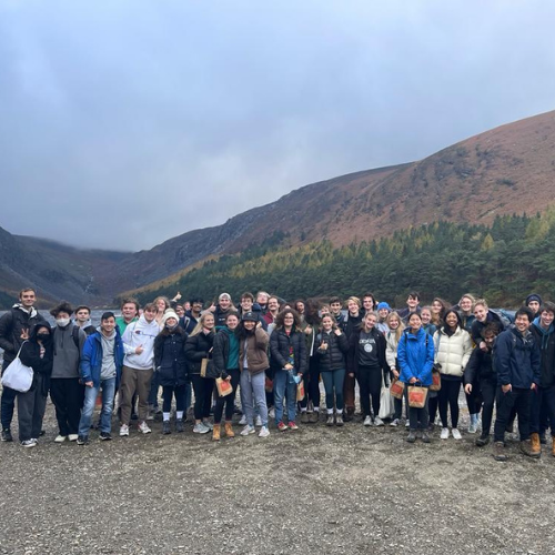 A group  of student stand on the shore of Glendalough lake.
