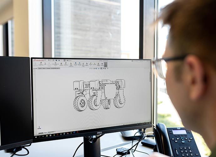 A man surveys a computer screen with mechanical engineering drawings.