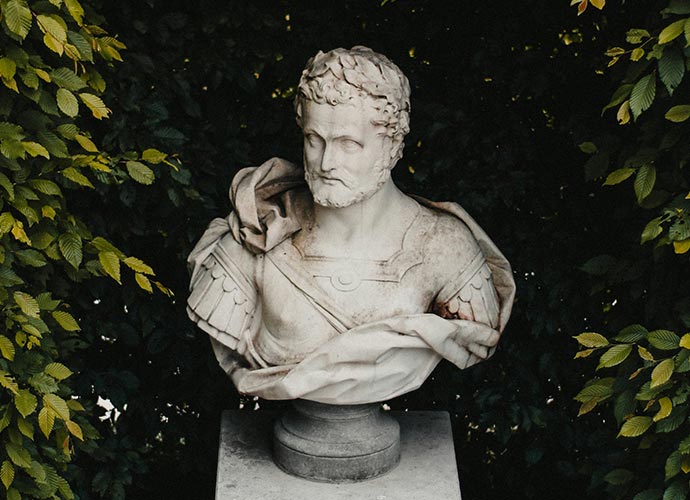 Marble bust of a Roman-style figure surrounded by greenery, representing classical thought and history.
