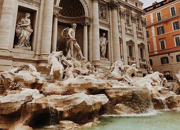 The Trevi Fountain in Rome, featuring ornate statues of figures and horses with cascading water in the foreground.