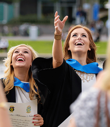 A group of students throw their mortarboard caps in the air.