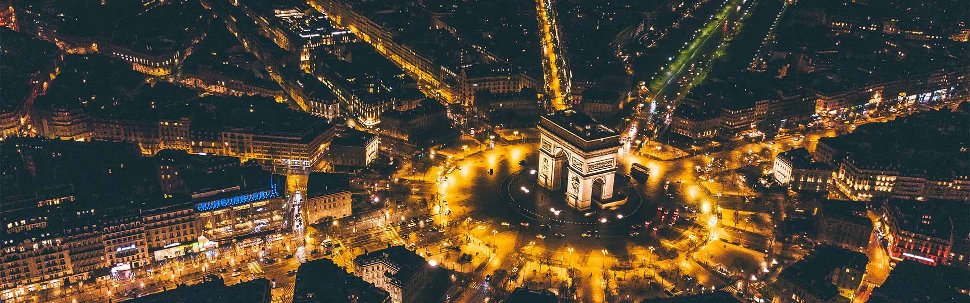 A night-time, aerial shot of the Arc de Triomphe.