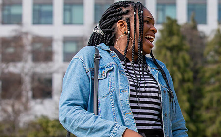 Woman laughs. She wears a denim jacket.