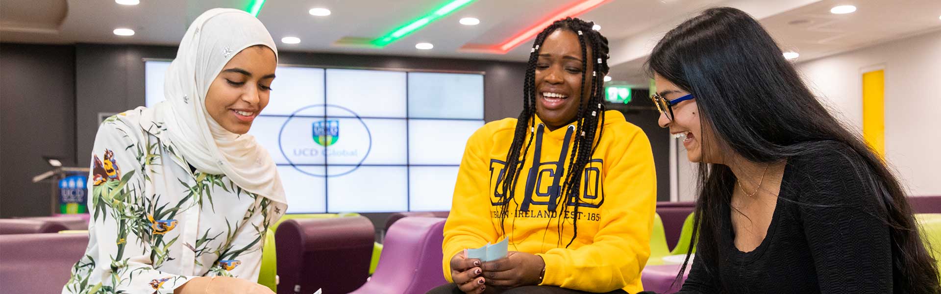 Three students laugh around a boardgame.