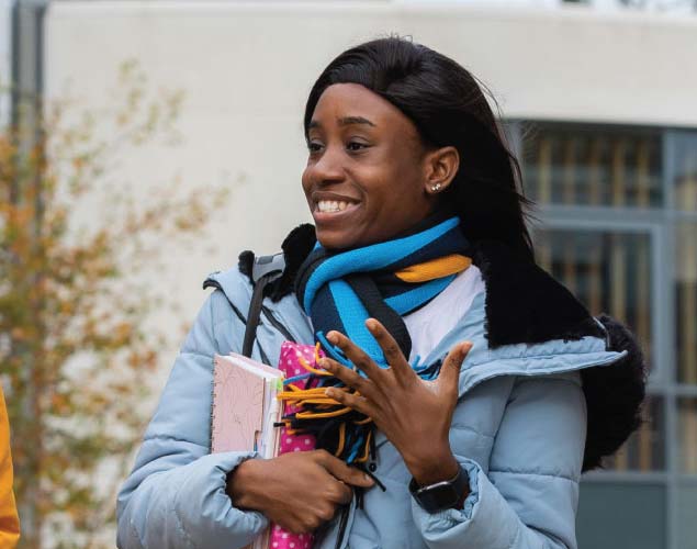 A young woman hold stationary and wears a UCD scarf.