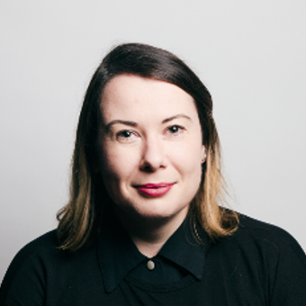 A headshot of a woman smiling wearing a black shirt with a white background