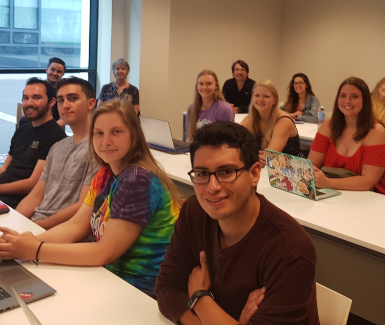 Students sitting at desks and looking towards the camera in UCD