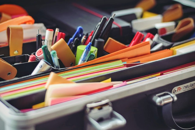 An image of pens and sticky notes inside a folder