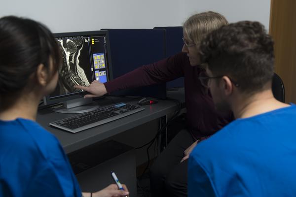 Two students in scrubs looking at xray with lecturer