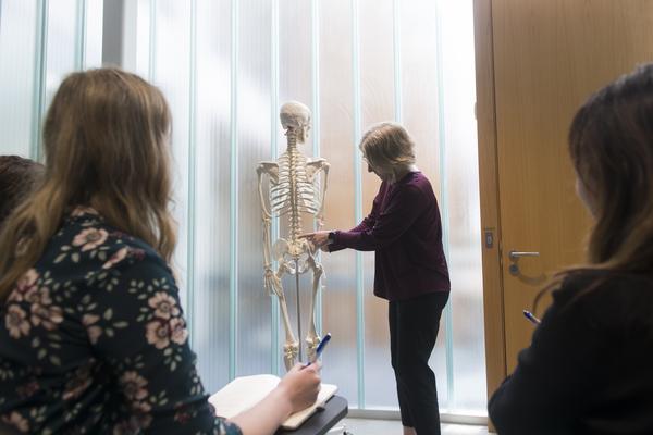 Lecturer showing students part of skeleton