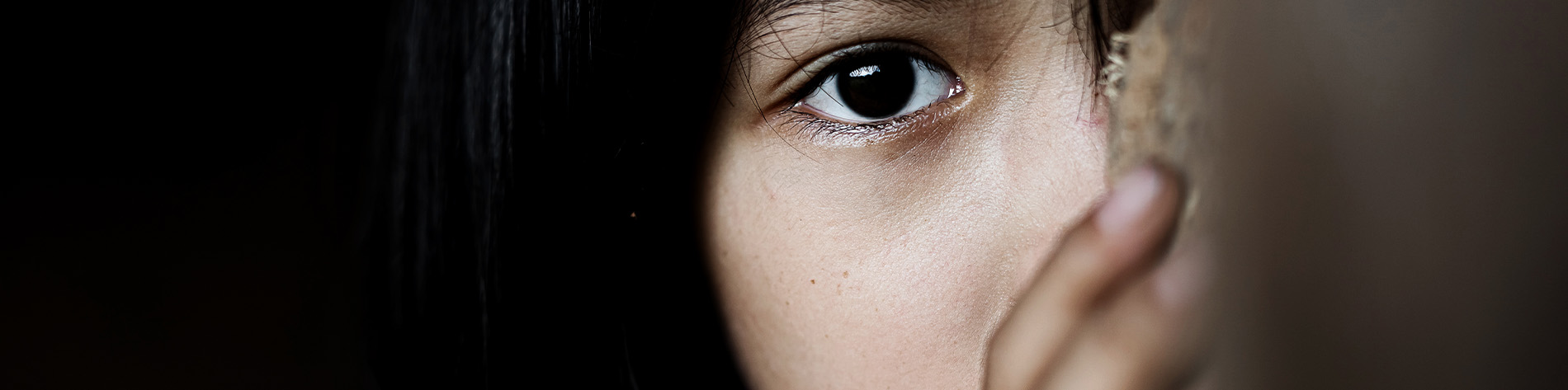 Girl peeking from behind a wall.