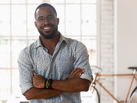 Male in blue shirt smiling with arms crossed.