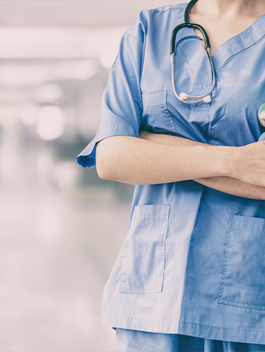 Woman in scrubs stands with her arms crossed.