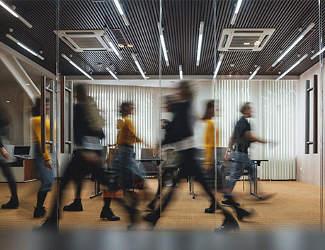 Blurred image of people walking in an office.