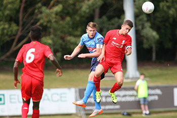 The captains of UCD and Liverpool contest a header