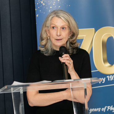 Woman in a black outfit speaking at the UCD Physiotherapy 70th anniversary celebration