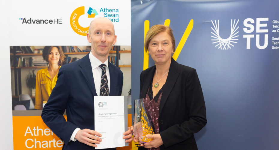A man and a woman holding a certificate and a glass award