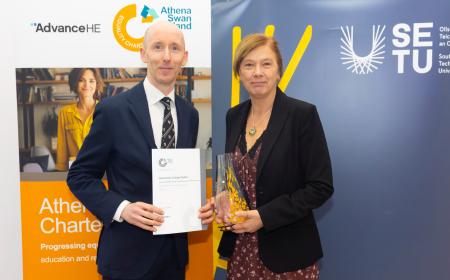 A man and a woman holding a certificate and a glass award