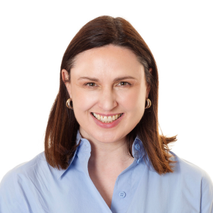 Woman with dark hair wearing a blue shirt smiling to camera