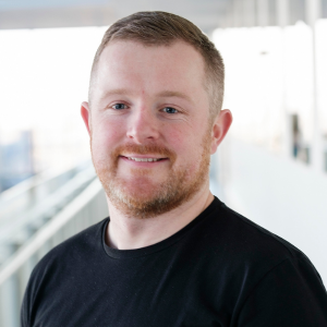 Man with beard wearing black top smiling to camera