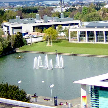 Looking over a lake from a height that is surrounded by UCD buildings