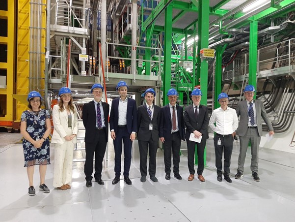 Minister Harris (4th from Left) beside Prof. McNulty (5th from Left) with UCD student Amanda Donohoe (2nd from Left) and former UCD student Dr. Karol Hennessy (2nd from Right), photographed underground at CERN in front of the LHCb detector (June 2023).