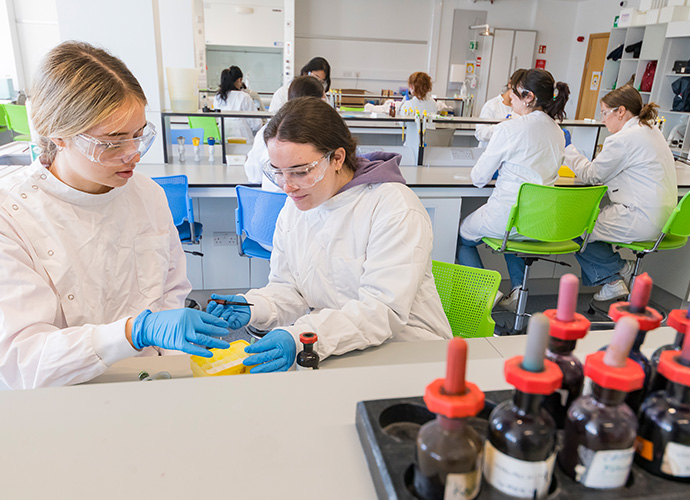 Students in safety gear working in a biology lab
