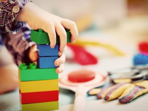 child's hand playing with duplo bricks