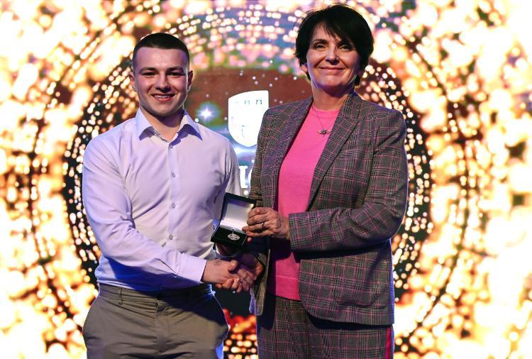 Rory Monks accepting the award on stage from UCD President Prof. Orla Feely