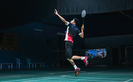 A badminton player jumping for a shot