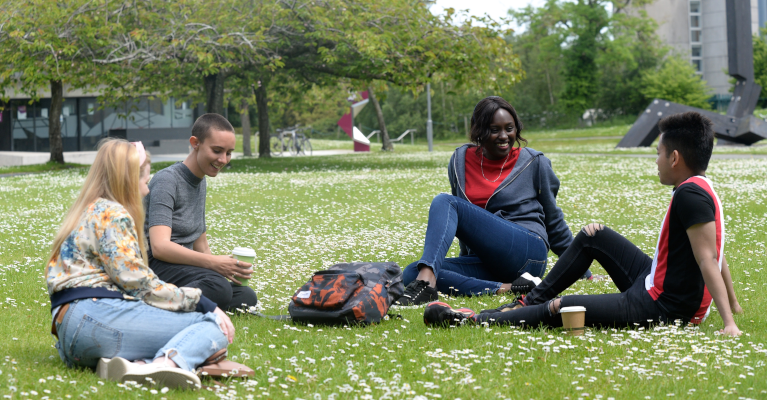 student sitting on grass on campus