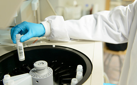 Close up of a researcher working with a centrifuge in a lab