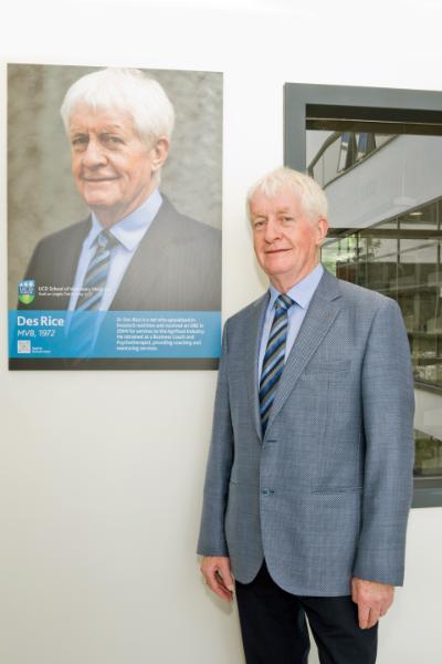 Des Rice beside his Alumni Wall photo